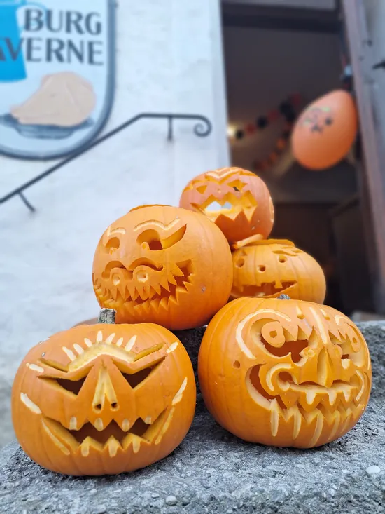 Gruppe geschnitzter Halloween-Kürbisse mit gruseligen Gesichtern auf Steintreppen